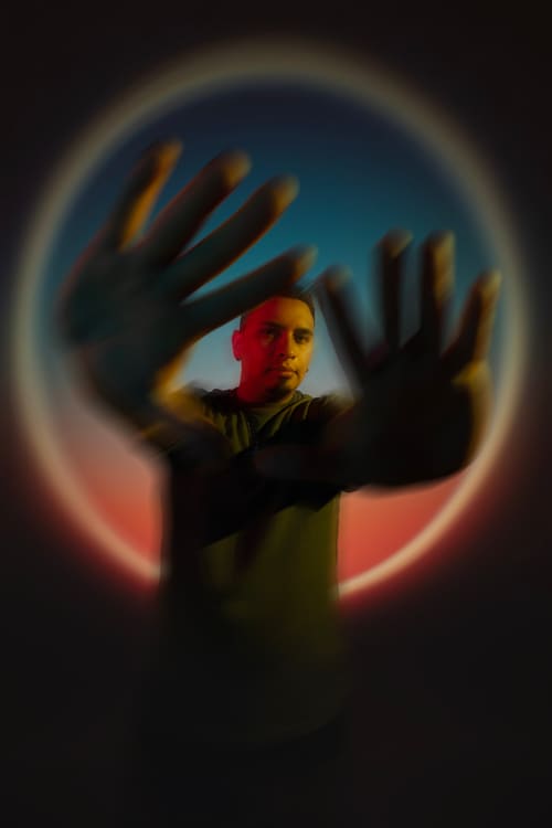 Mateo Saldarriaga con las manos extendidas dentro del halo de luz de la banda.